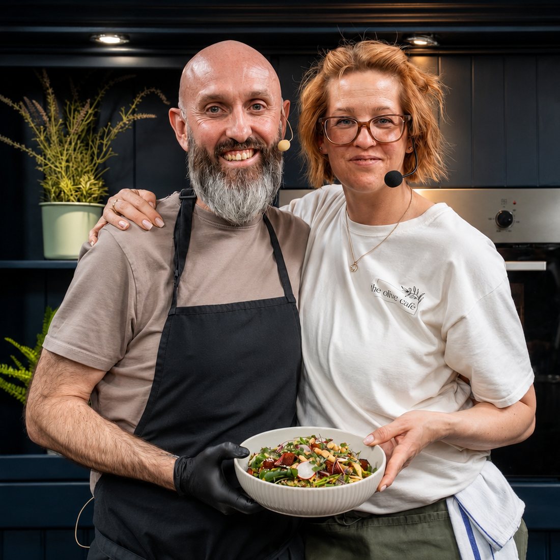 Wayne and Krisztina smiling together, holding a bowl of fresh salad
